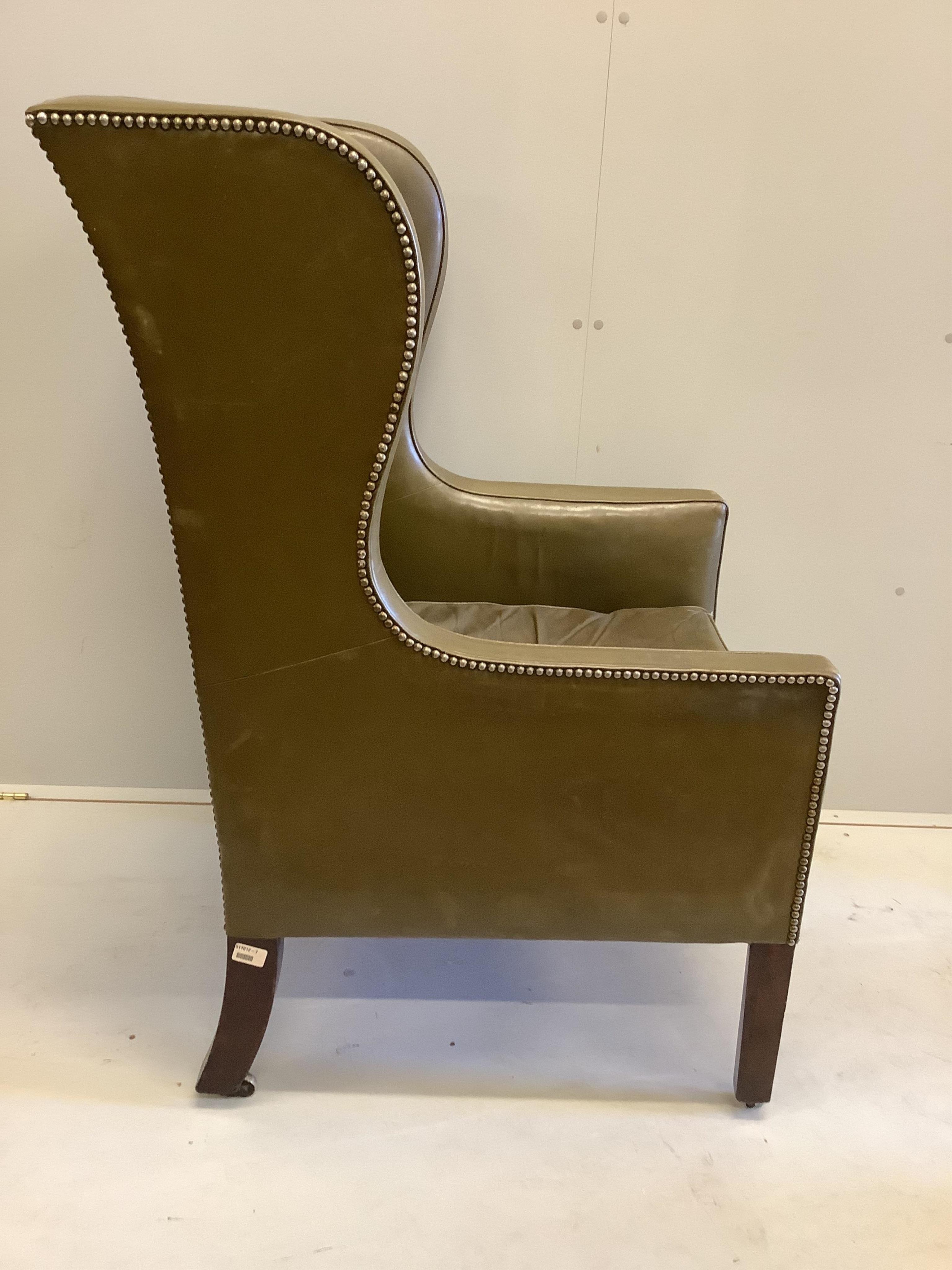 A George III wing armchair with olive leather upholstery, width 70cm, depth 70cm, height 115cm. Condition - fair